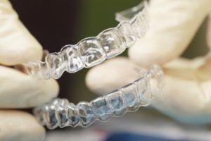 Close up image of a dentist holding a set of clear bite guards