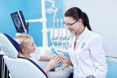 Female dentist treating child seated in a dental chair
